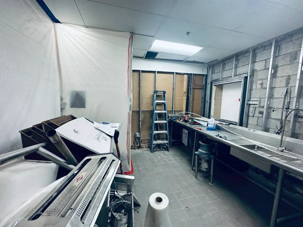Commercial kitchen with an exposed wall and protective sheeting