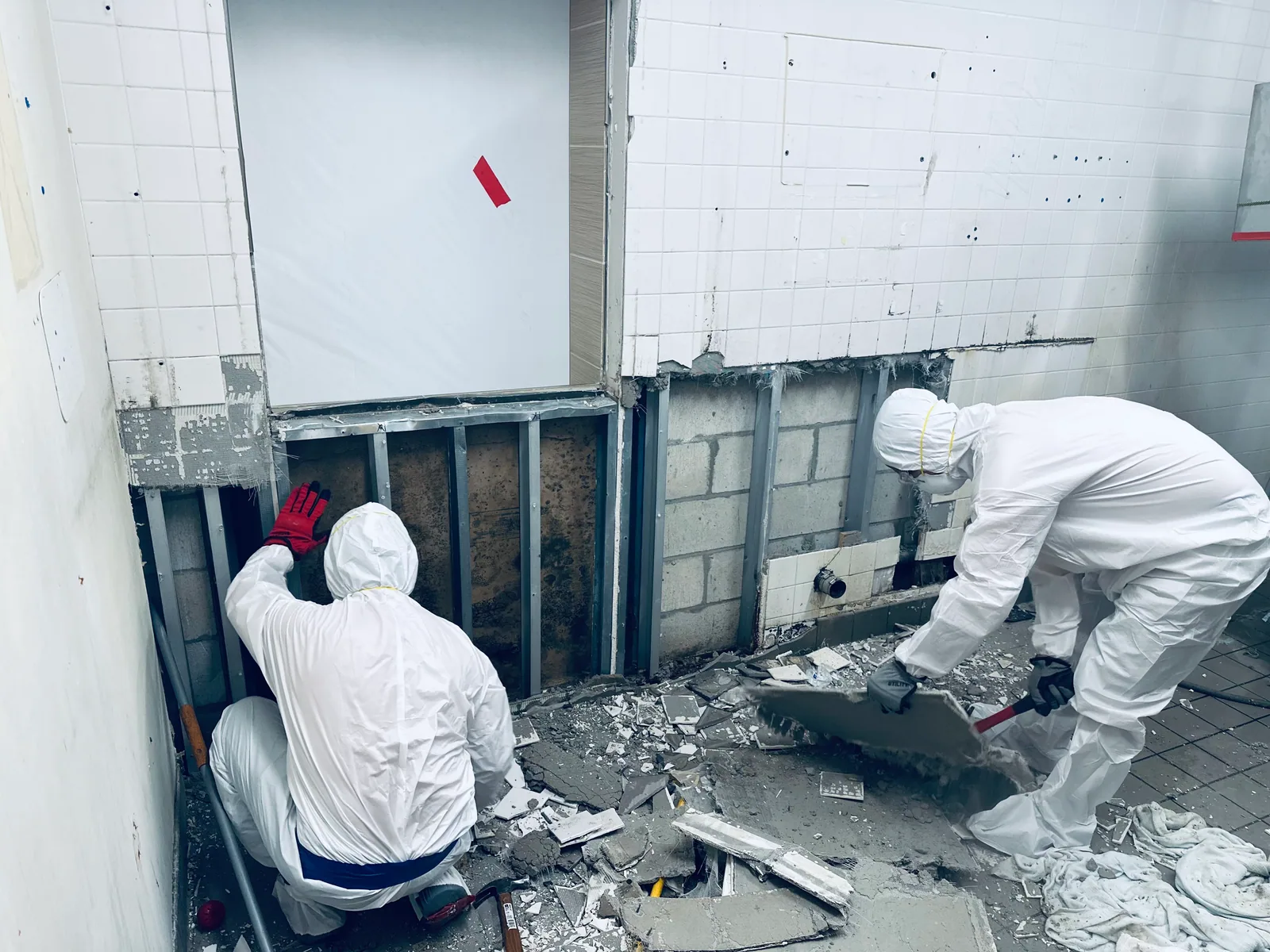 Workers removing debris beside exposed wall framing