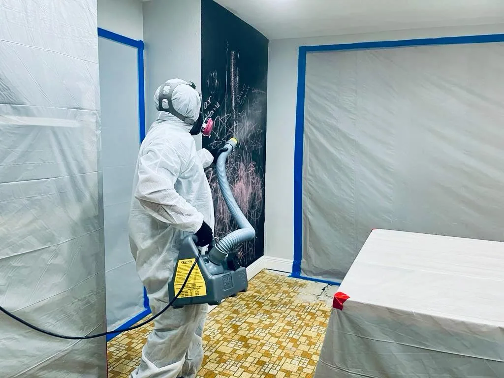 Worker using cleaning equipment inside a contained kitchen