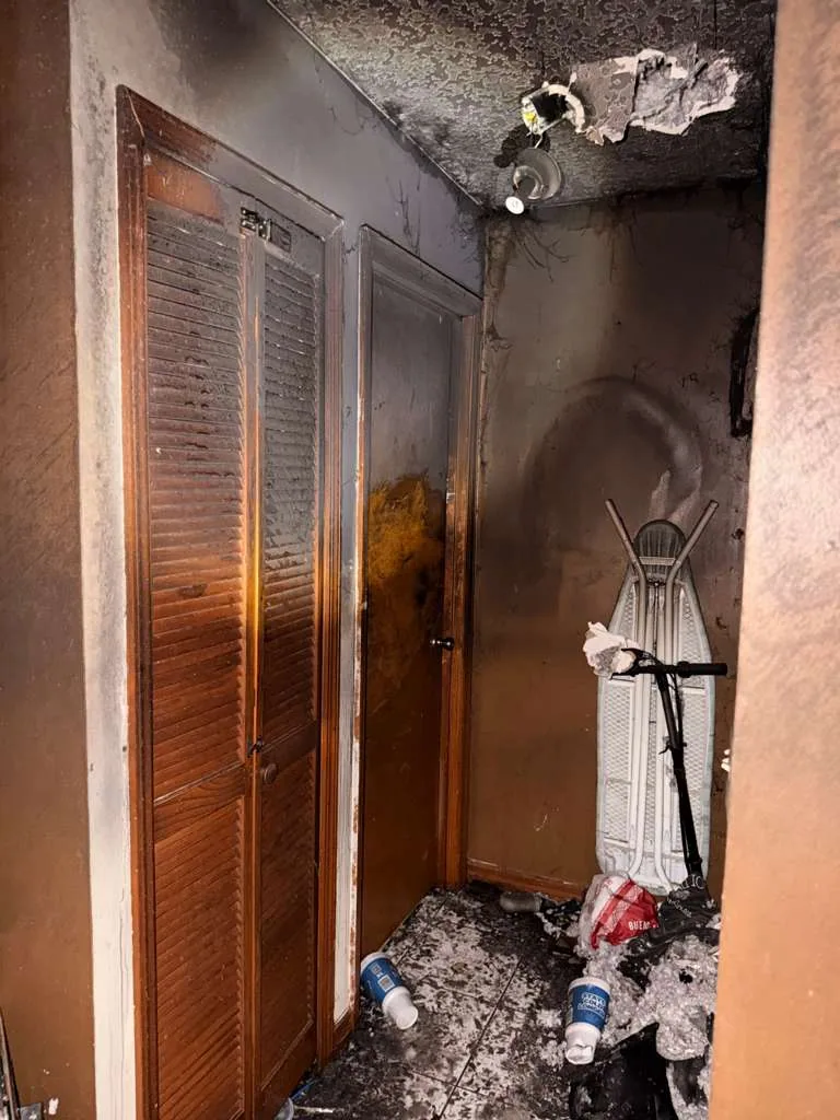 Corredor danificado pelo fogo com portas de armário danificadas e detritos