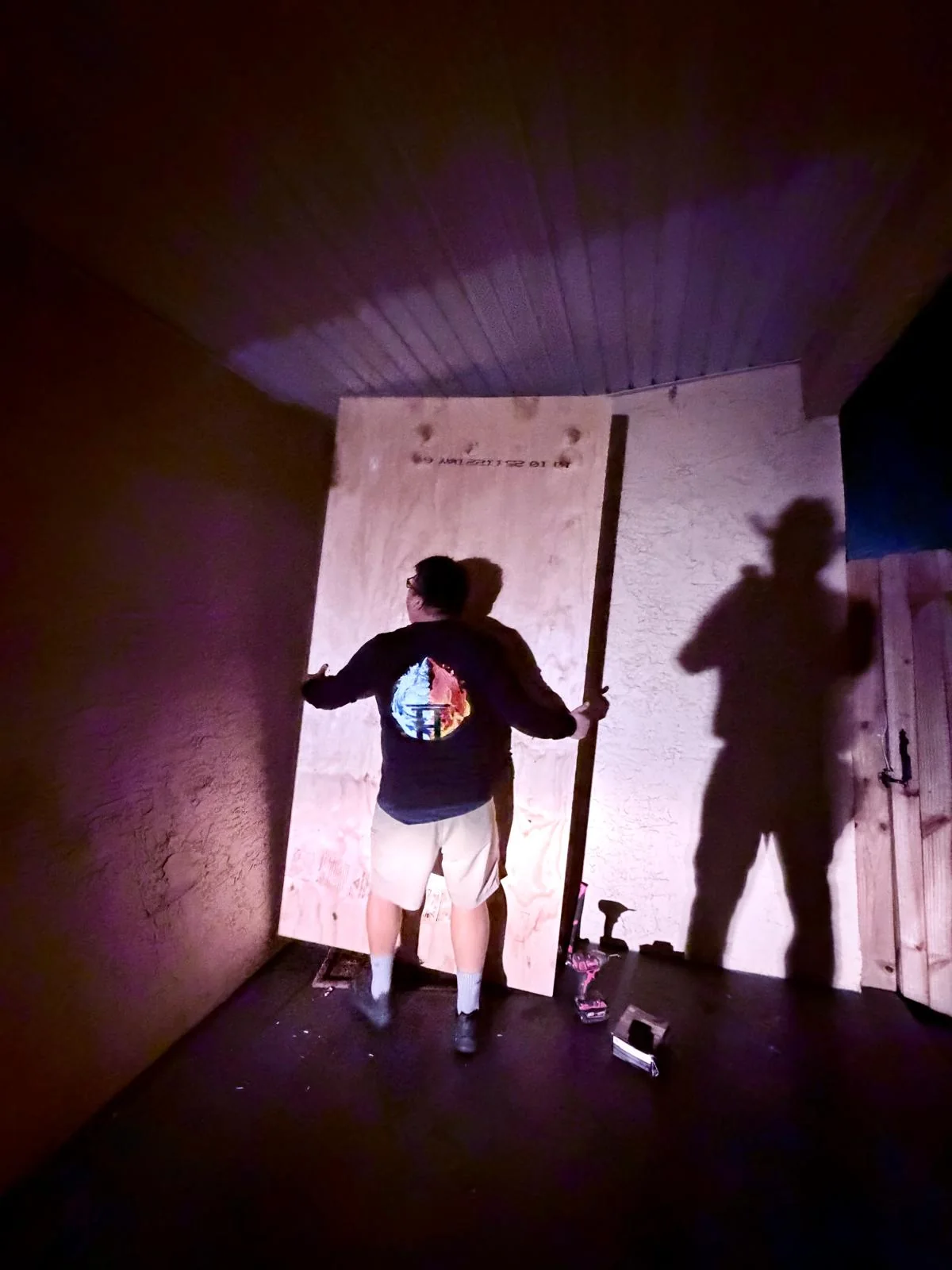 Worker securing plywood across a doorway after dark