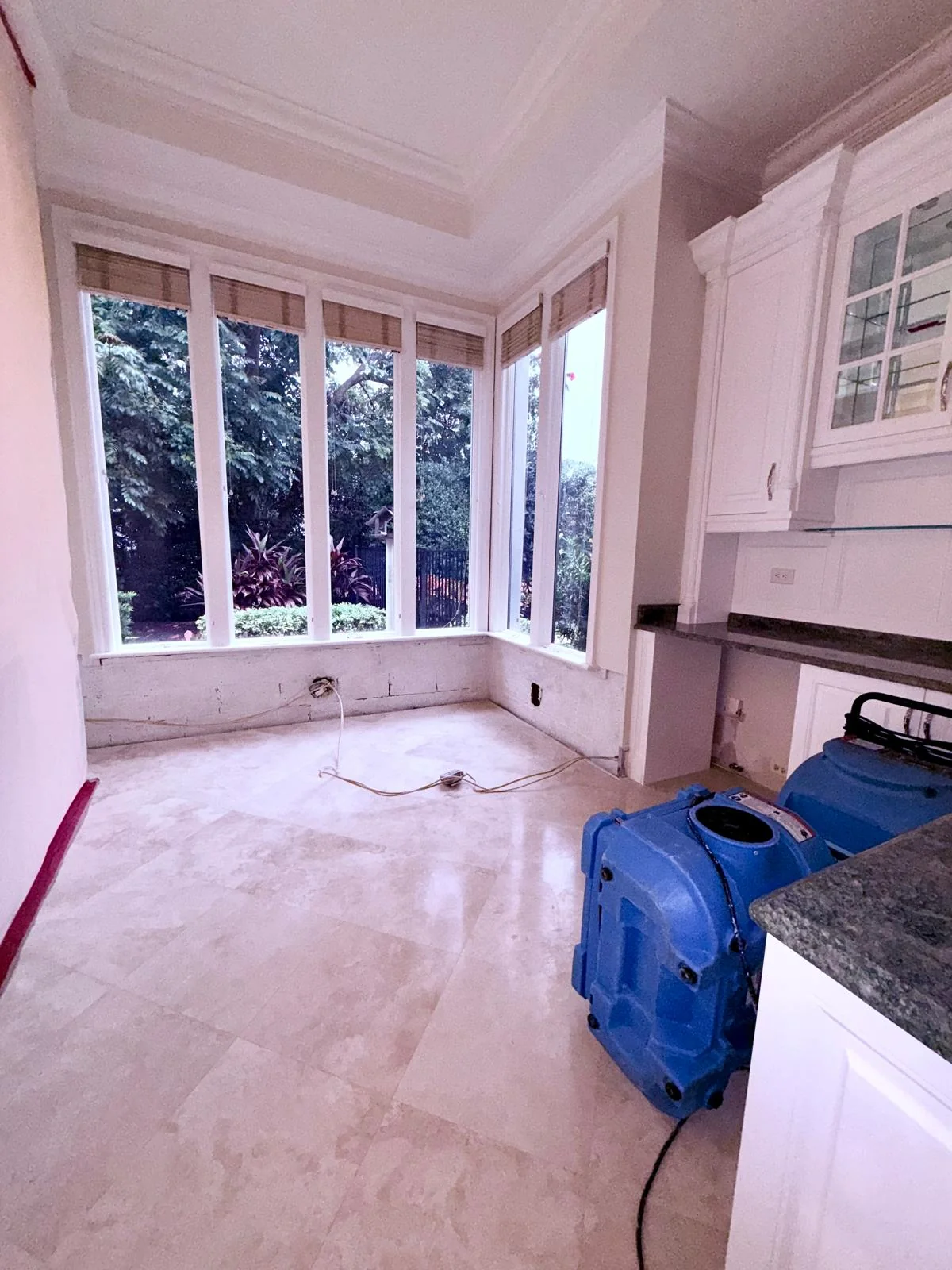 Air mover beside cabinets in a room with large windows