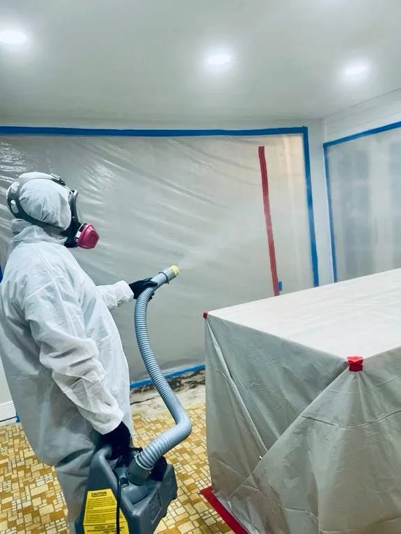 Trabajador limpiando una superficie dentro de una habitación confinada