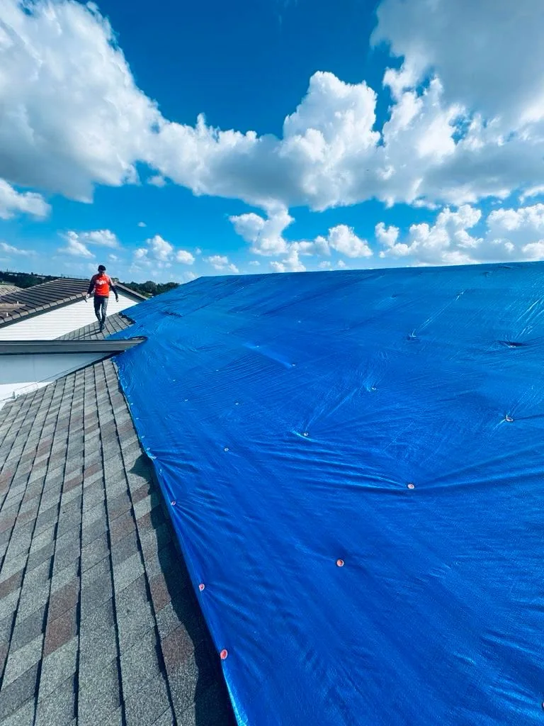 Blue tarp covering part of a shingle roof