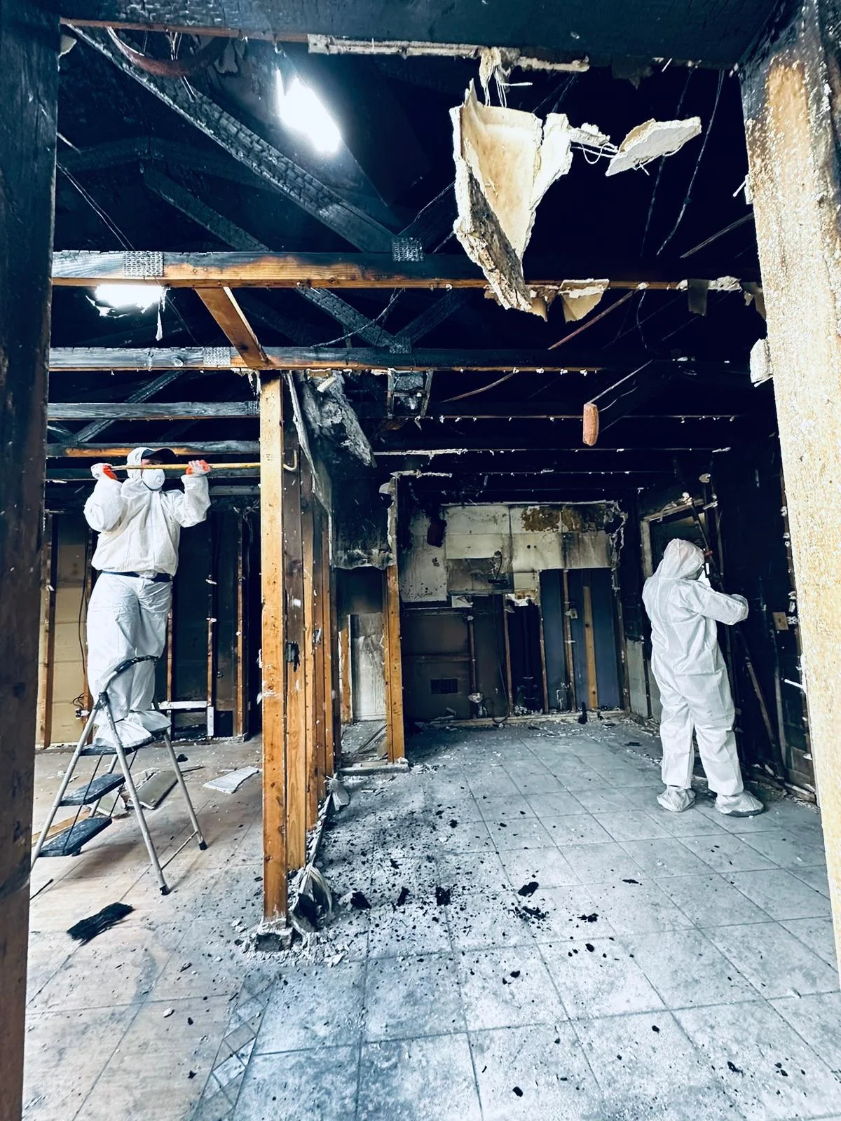 Workers cleaning exposed framing in a fire-damaged building