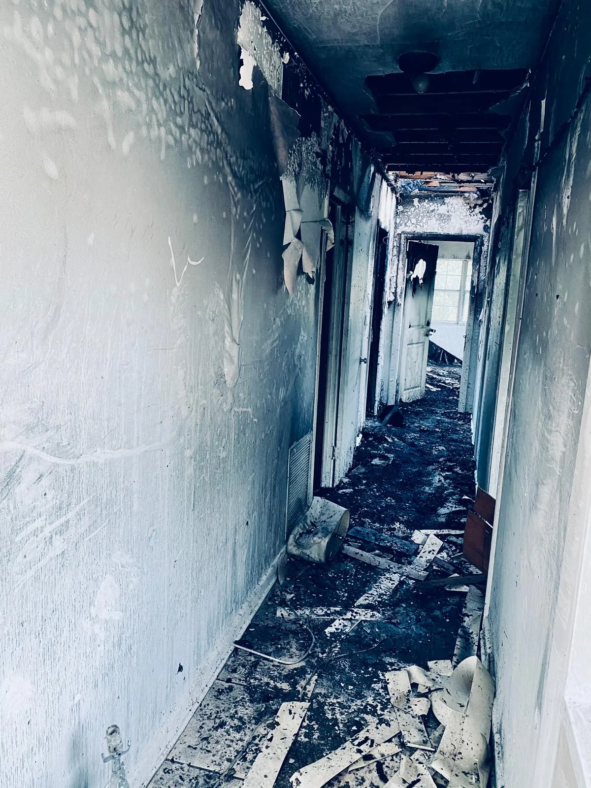 Fire-damaged hallway with debris on the floor