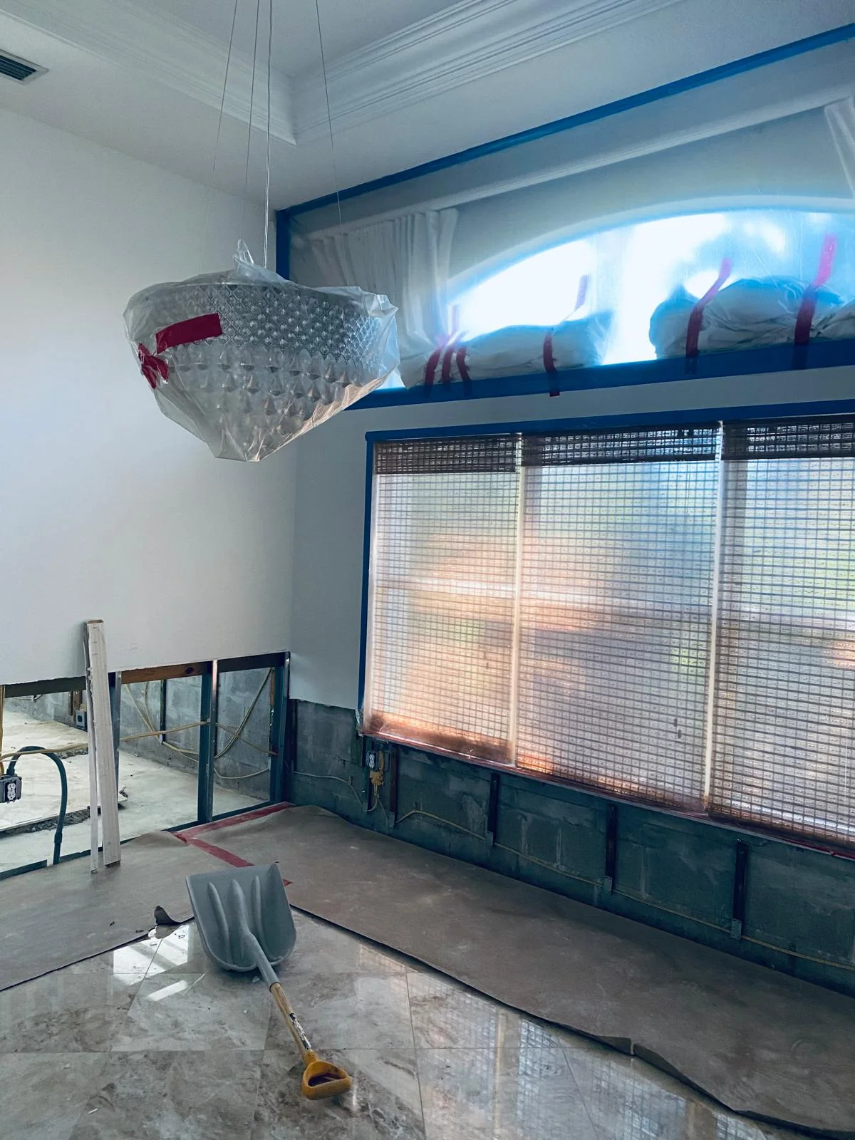 Protective sheeting covering a large opening beside a chandelier