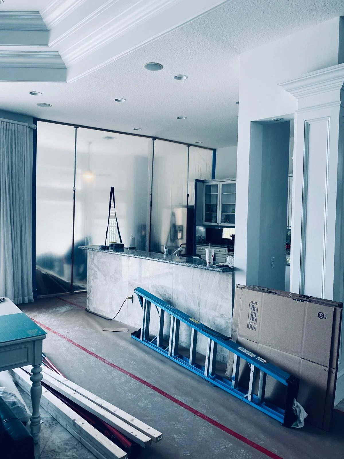 Protected flooring and a ladder in a room undergoing restoration