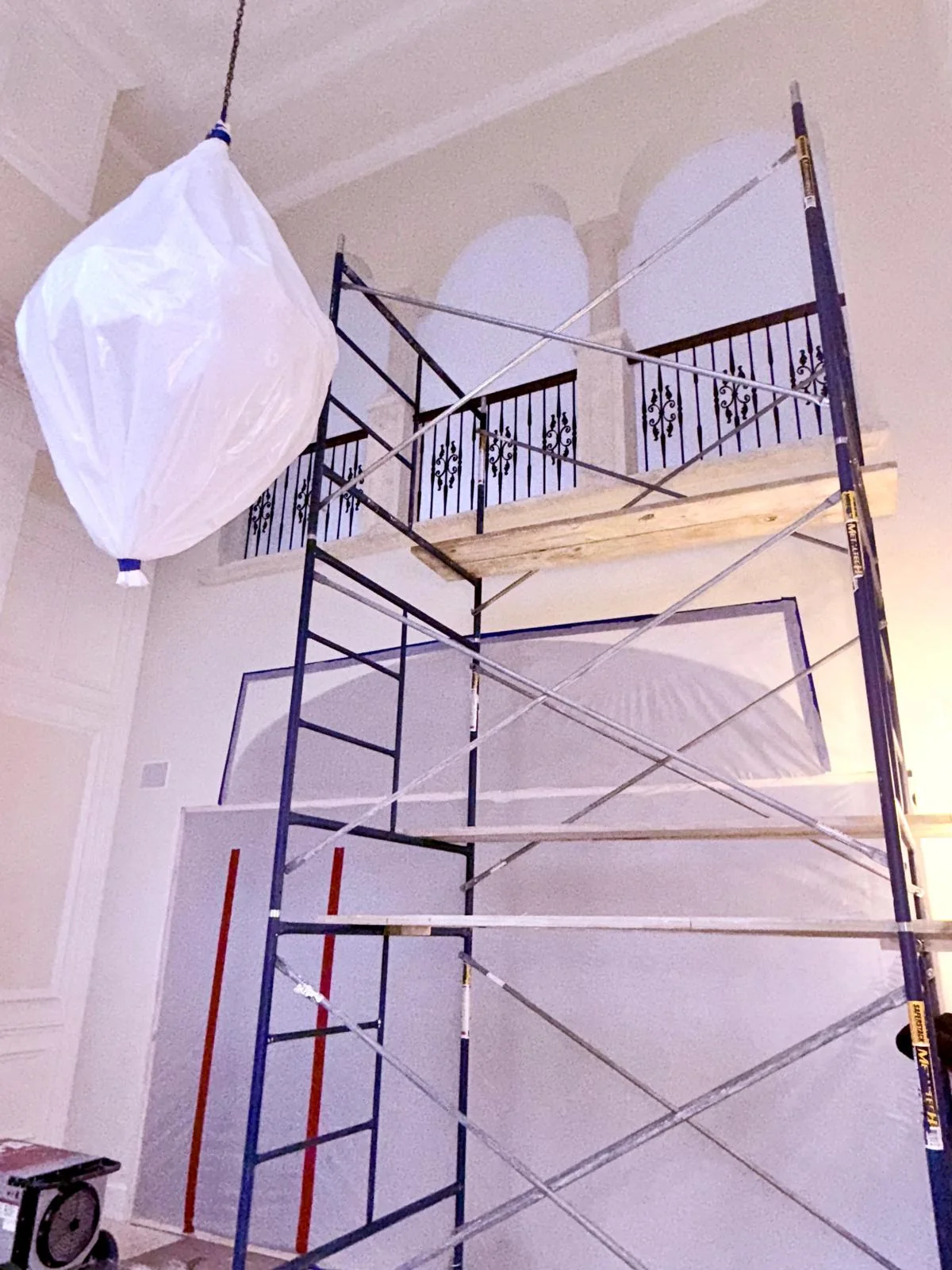 Scaffolding beside tall windows and protective sheeting