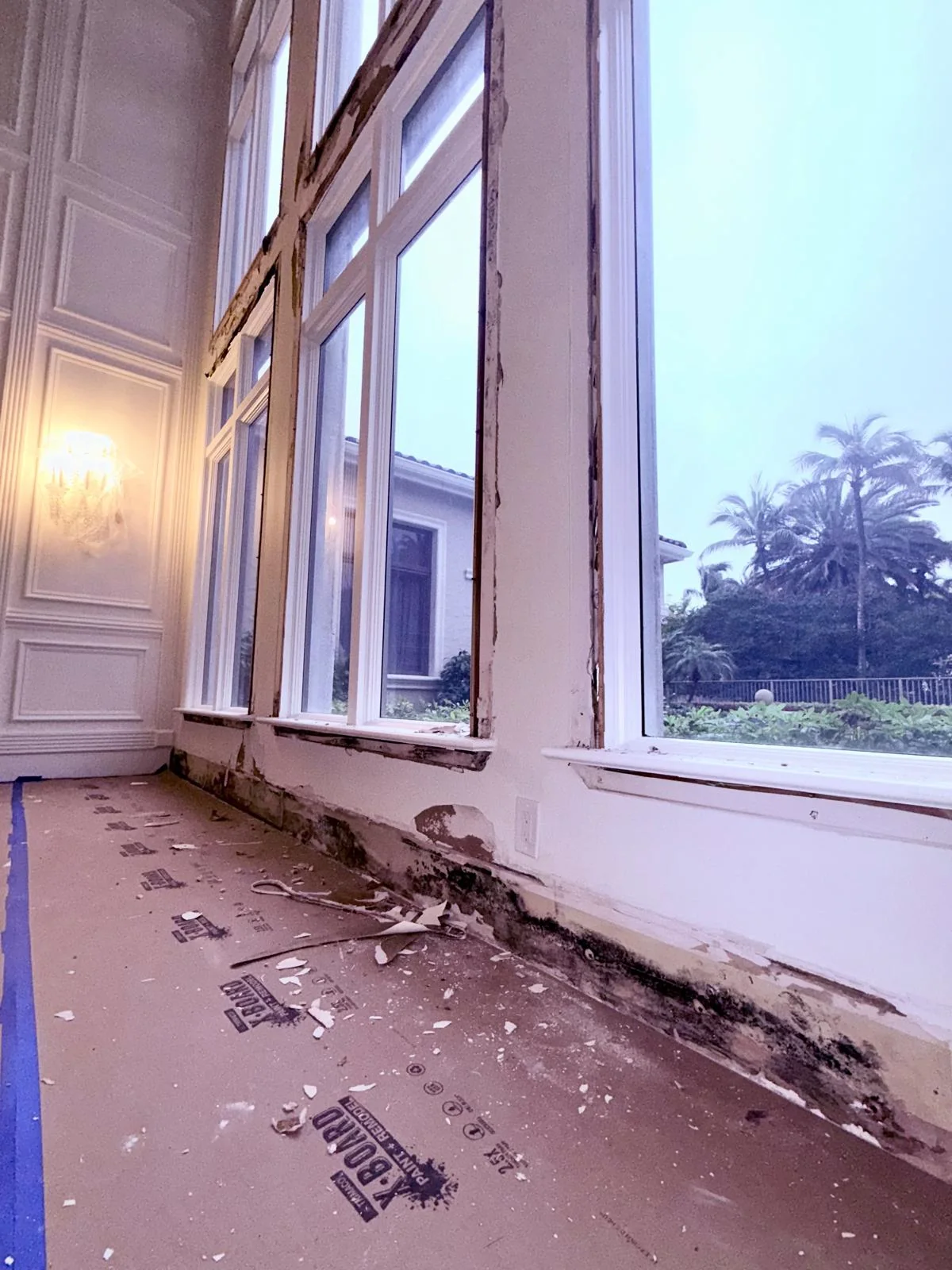Damaged material beneath a row of tall windows