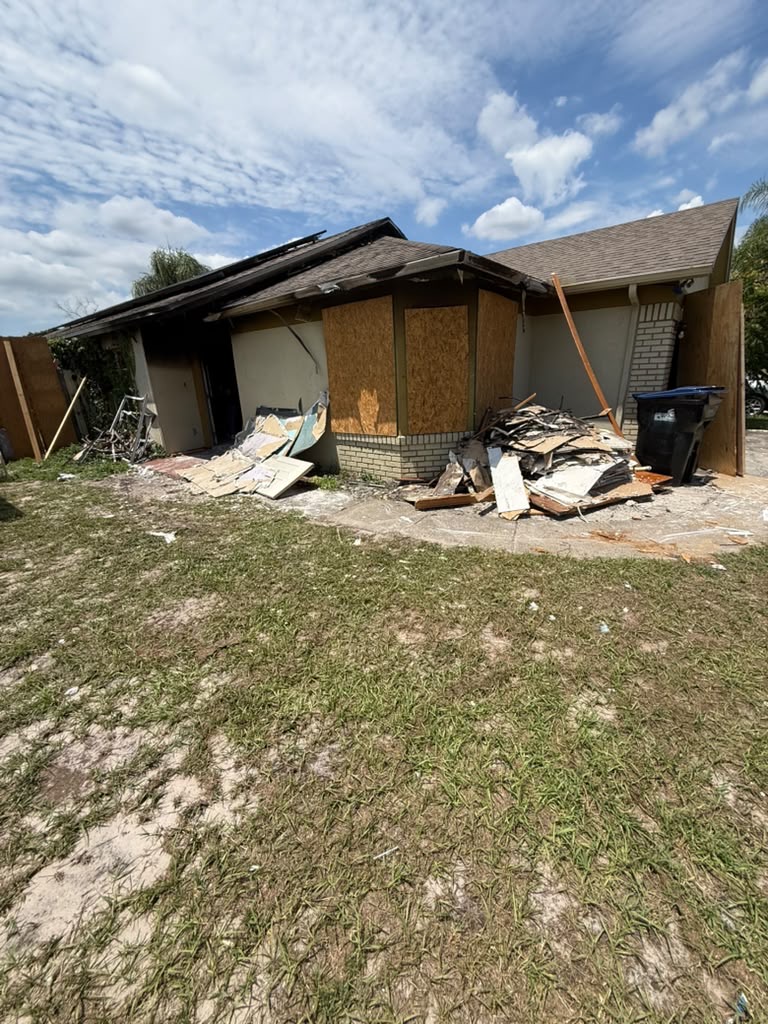 Boarded house exterior with damaged building materials collected beside the driveway