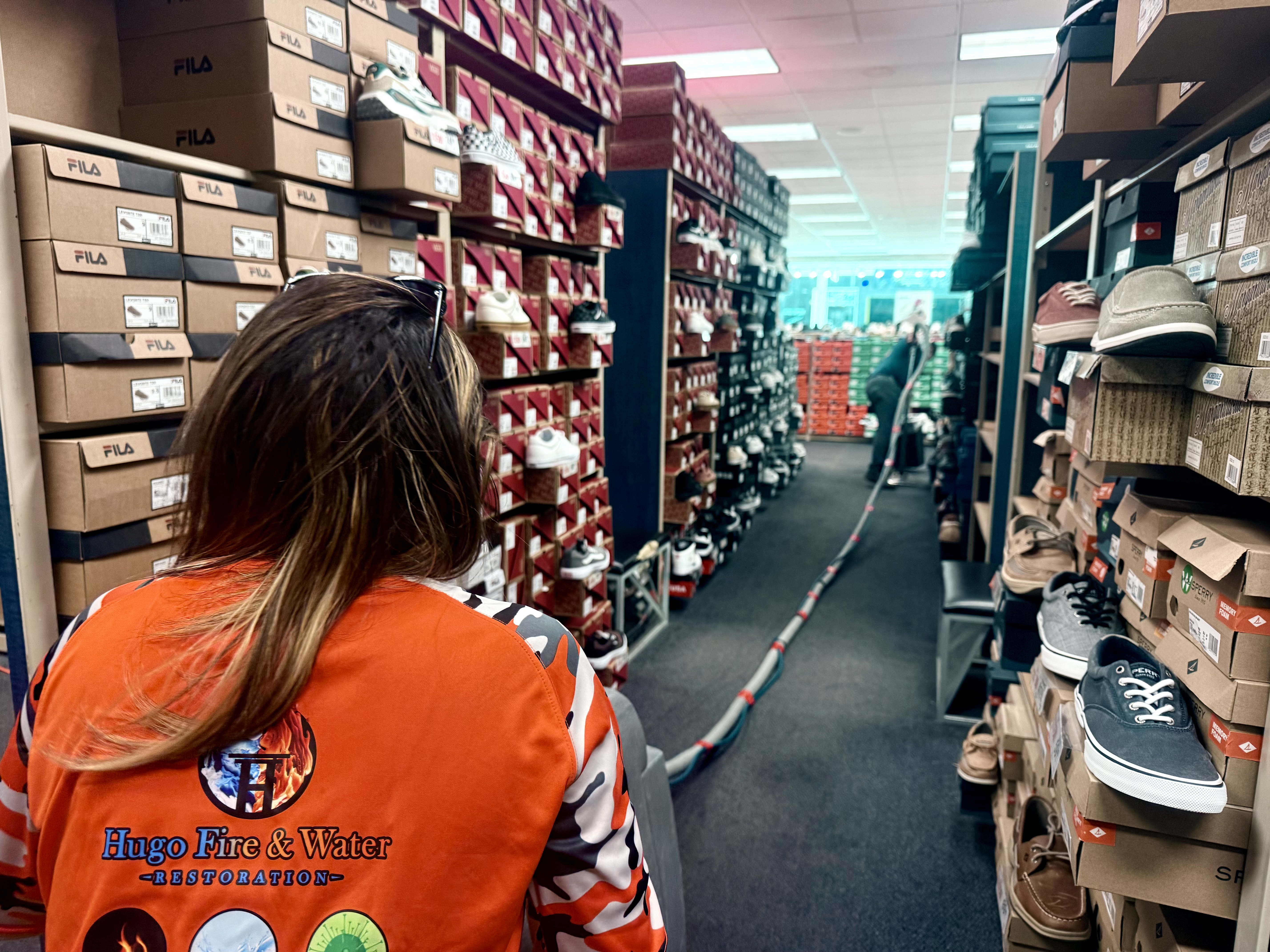 Worker in a branded shirt in a retail aisle lined with footwear