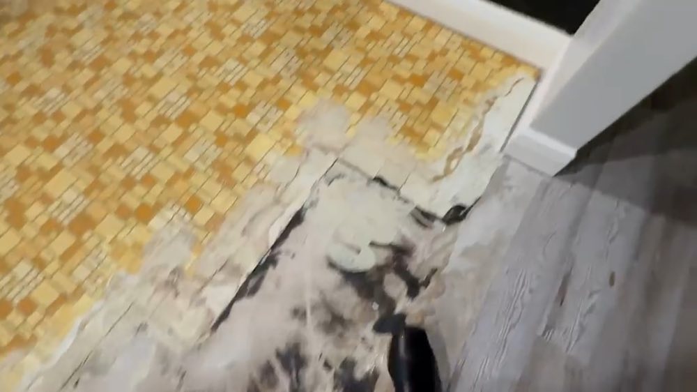Damaged flooring beside a yellow tile floor