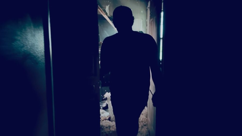 Pessoa andando por um corredor escuro e danificado