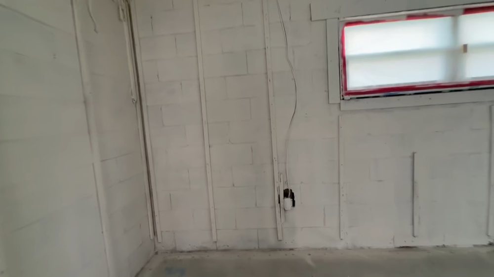 Pared de bloques con cableado expuesto y una pequeña ventana