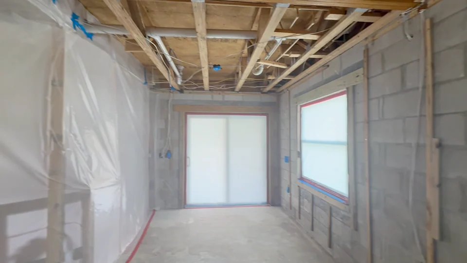 Open ceiling framing above a room enclosed by protective sheeting