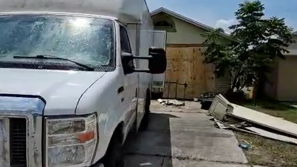Service truck outside a home with a boarded opening